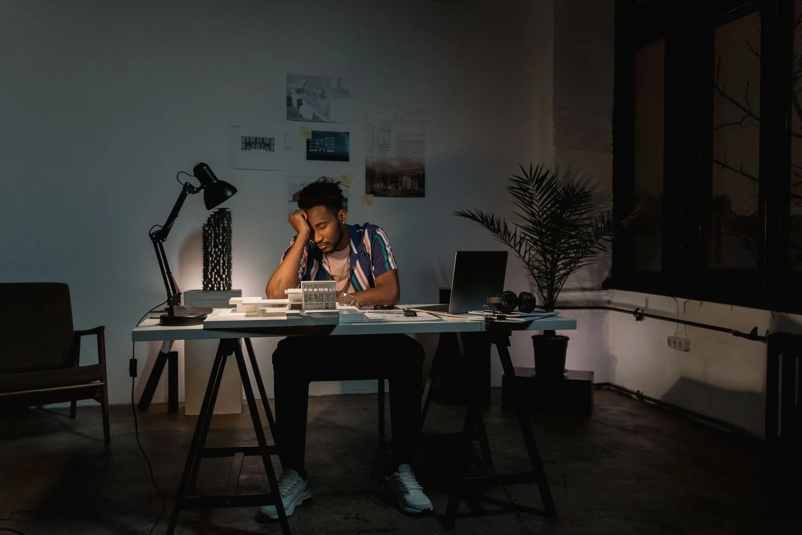 Un homme seul à son bureau le soir, la tête appuyée sur la main