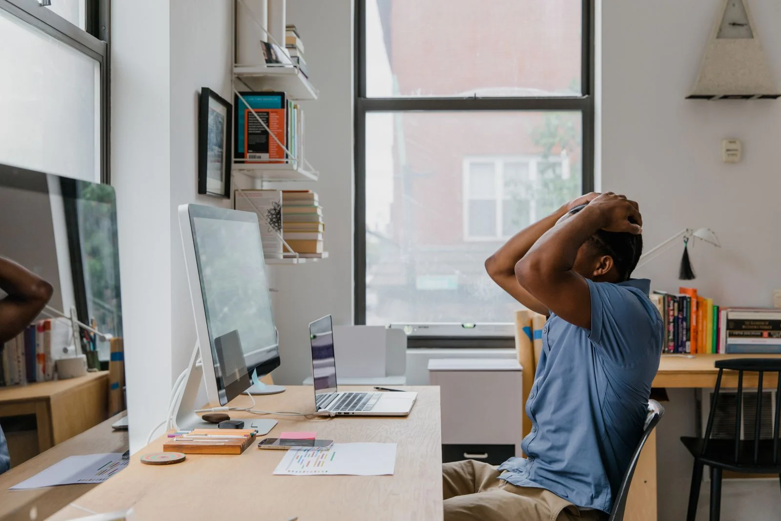 Un homme assis à son bureau devant son ordinateur, les mains croisées derrière la nuque